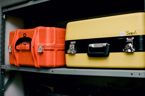 Traditional surveying equipment in their cases on a shelf.