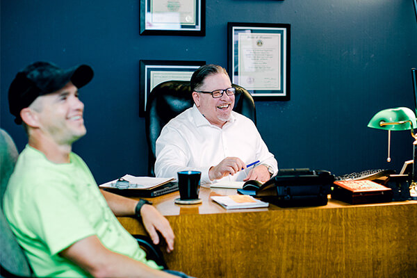 Two land surveyors discuss a project in an office. 