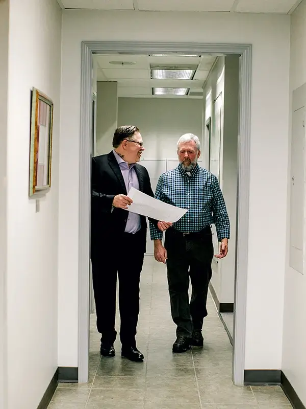 Two surveyors discussing plans while walking through the office