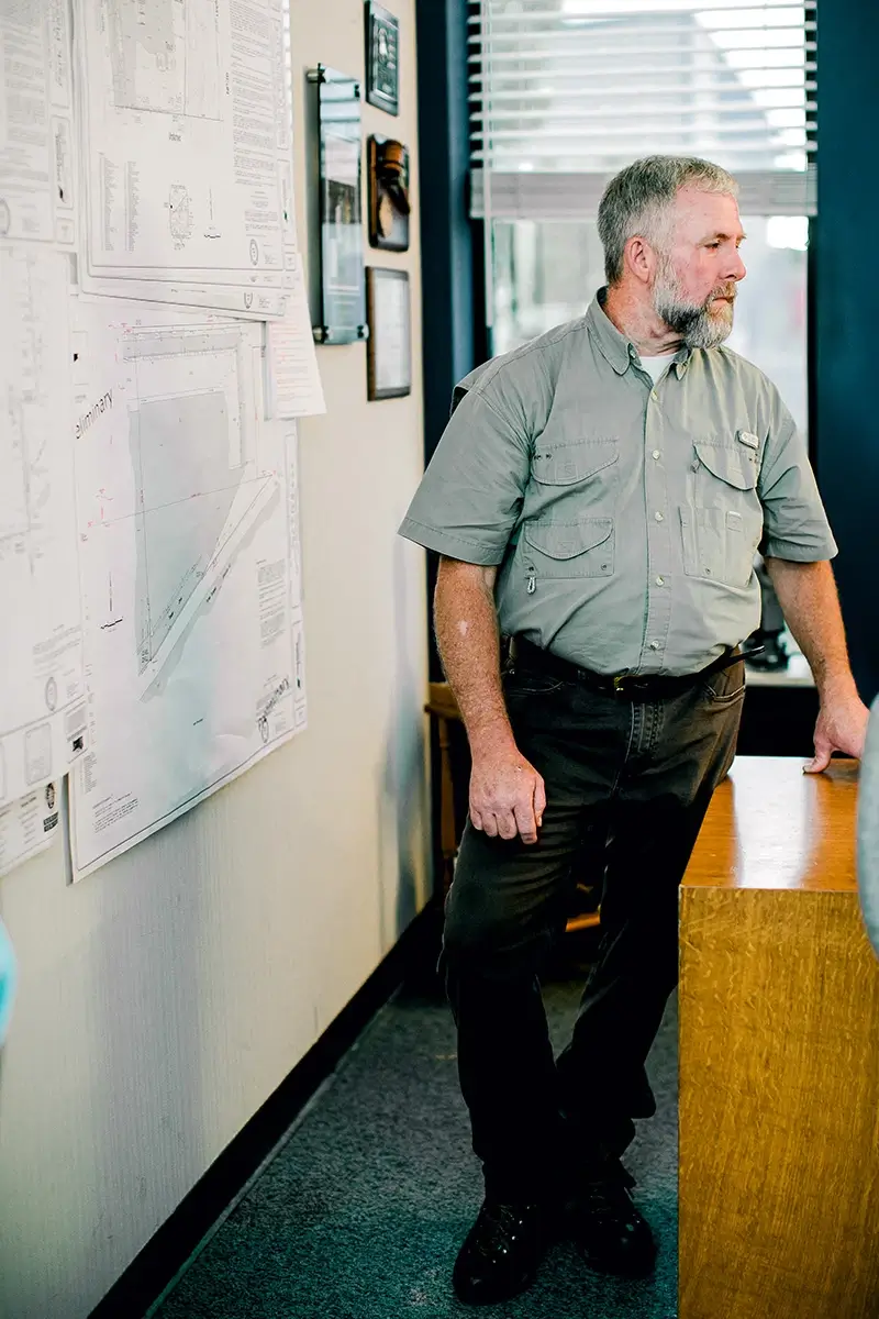 A surveyor standing next to a map hanging on a wall